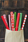 Rolls of red and green gift wrap in paper bag