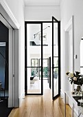 Flur mit offener, schwarzer Glasflügeltür und Durchblick auf Wohnbereich und Galerie