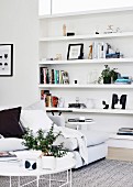 White coffee table and sofa in front of an open shelf