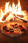 Auf Stein gebackene Pizza mit Käse, Tomaten und Blutwurst im Holzofen