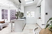 Open kitchen with light gray, freestanding counter in country house style in a restored old building