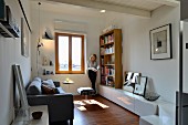 Renoviertes Wohnzimmer mit lesender Frau zwischen Bücherregal und Fenster