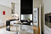 White bar stools in front of black partition with fold-up, glossy table top