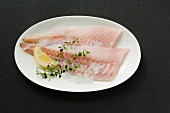 Rose fish fillets with lemon wedges and thyme