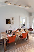Herbstlich gedeckter Esstisch mit orangefarbenen Stühlen