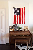 Piano and piano bench below flag of the United States on wall