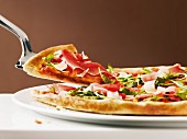Pizza with raw ham and rocket, sliced