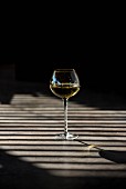 Shadows playing over a glass of white wine