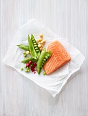 Salmon fillet with peas, chickpeas and cranberries on a piece of paper