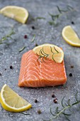 Raw salmon fillet with lemons, rosemary and pepper