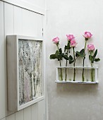Konsole an Wand mit Rosen in Reagenzgläsern, seitlich aufgehängtes Kunstobjekt