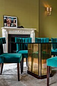 Dining table with mirrored base and petrol-blue upholstered chairs in grand dining room