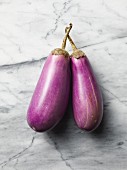 Two aubergines on a marble surface