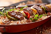 A lamb kebab with peppers on a bed of rice