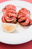 Grilled octopus with a lemon wedge on a plate