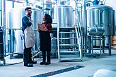 A beer brewer and a colleague taking in front of beer tanks (USA)
