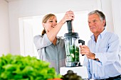 A man and a woman making a vegetable smoothie in a kitchen