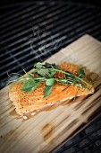 More salmon fed with herbs and spices on smoking board on a grill