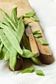 Green beans with a knife on a wooden chopping board