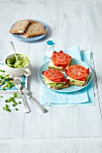 Open sandwiches topped with green pea and avocado cream, cheese, grilled peppers and tomatoes