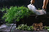 Fresh dill and thyme with an old pair of scissors, twine and a chopping knife on an old wooden table (seen from above)