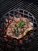 A rib-eye steak with herbs on a barbecue