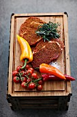 Spiced beefsteak for grilling with vegetables and herbs on a chopping board