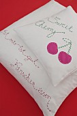 Hand-made scatter cushions with embroidered mottos and cherry motif