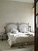 Französisches Bett mit Kopfteil aus Holz in Grautönen, Beistelltisch mit Tischlampe im Schlafzimmer
