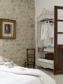 Rustikales Schlafzimmer mit offenem Kleiderschrank und Natursteinwand