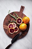 Blood oranges, whole and sliced on a wooden chopping board (seen from above)