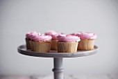 Cupcakes with pink cream frosting on a cake stand