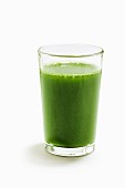 A green wheatgrass smoothie on a white surface