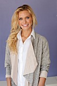 A young blonde woman wearing a white blouse and a grey shirt jacket