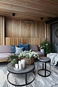 Upholstered furniture and round tables on wood-panelled modern terrace