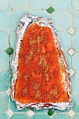 Salmon sprinkled with grilling spices on a piece of aluminium foil