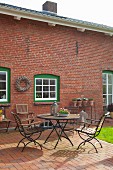 Summery terrace outside renovated brick house with white lattice windows in green frames