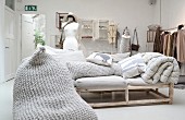 Sofa mit Polstern auf Holzgestell aus Rundhölzern, Kissen mit Häkelbezug im Verkaufsraum