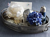 Blue hydrangea flower in small vase, alarm clock and salt cellar on silver tray