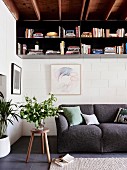 Metal hanging shelf for books on a cozy anthracite-colored upholstered couch in a 70s living room