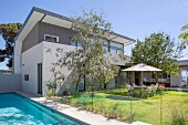 Architect's house with pent roof, pool and garden with seating under a parasol