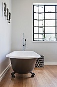 Puristisches Badezimmer mit freistehender Badewanne auf Holzboden