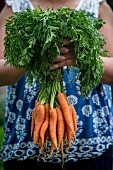 A woman holding a bundle of carrots