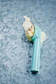An ice cream scoop with a scoop of melting vanilla ice cream and sugar sprinkles