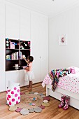 Children's room with bed and floor-to-ceiling wardrobe, girl in front of alcove