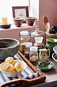 Storage jars, ceramic crockery and pastries on wicker tray