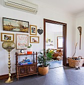 Vorraum mit orientalischer Stehleuchte, Regalschrank, Bildern und Zimmerpflanze, Blick ins Wohnzimmer