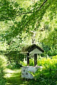 Nostalgischer Ziehbrunnen mit bemoostem Holzdach im Garten