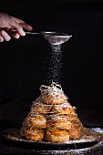 A croquembouche being dusted with icing sugar