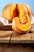 A sliced Muscade de Provence pumpkin and a wedge of Muscade de Provence on a rustic wooden board